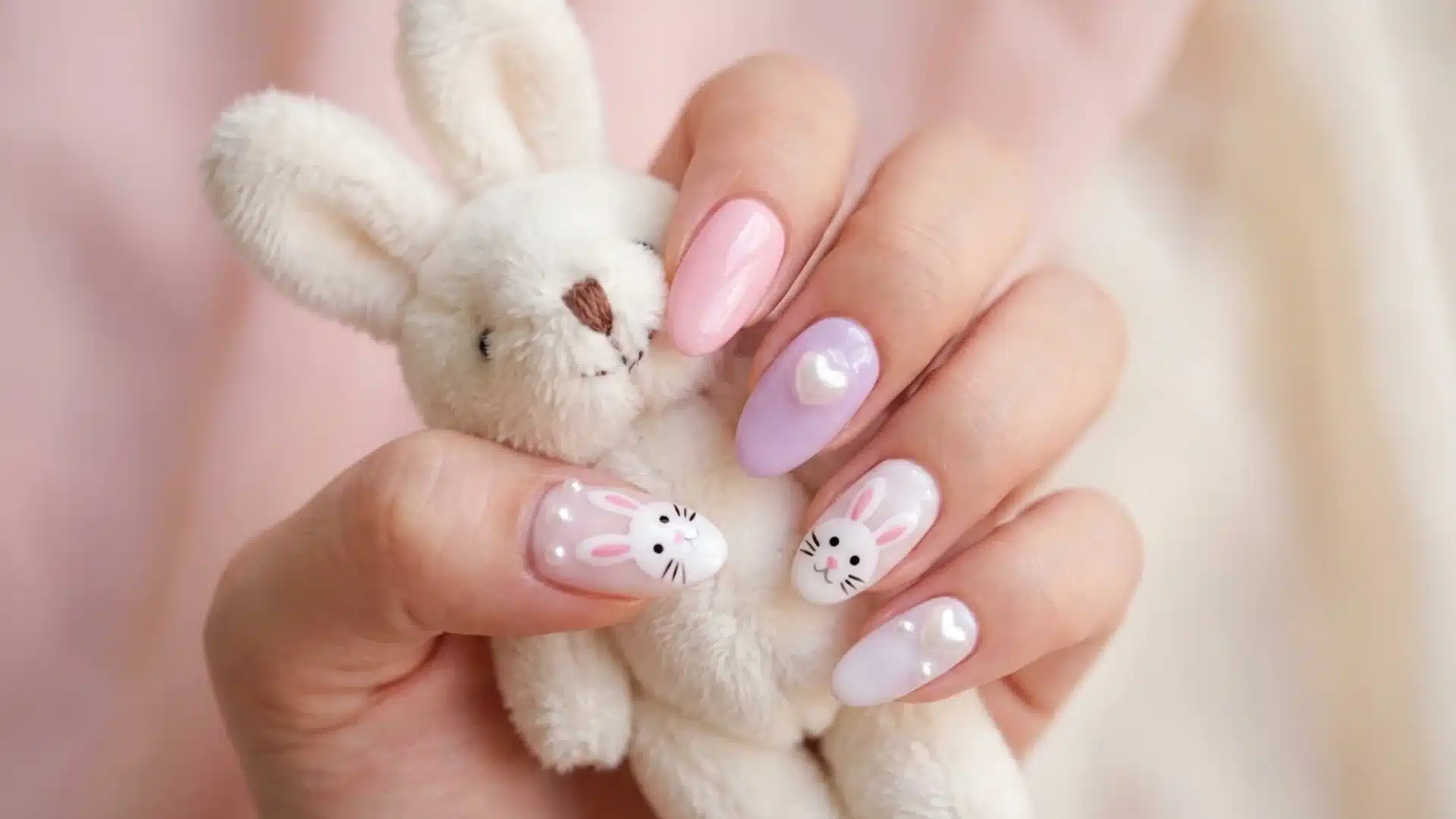 Hand with almond Bunny Charm nails in pastel pink and lavender, featuring cute bunny nail art