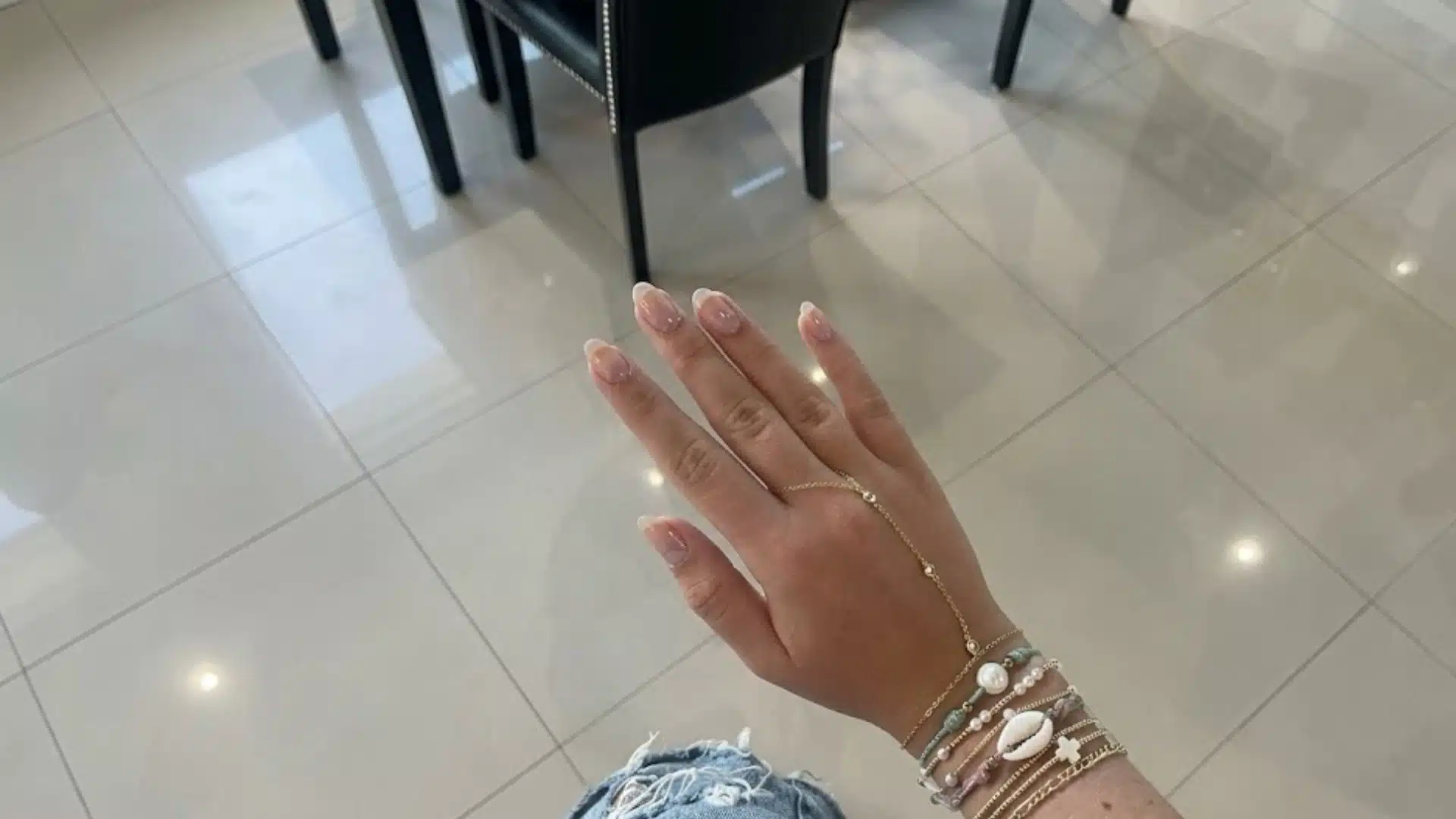 Hand with Bare Gloss nails in sheer nude pink, natural oval shape with glossy finish, minimal clean manicure style