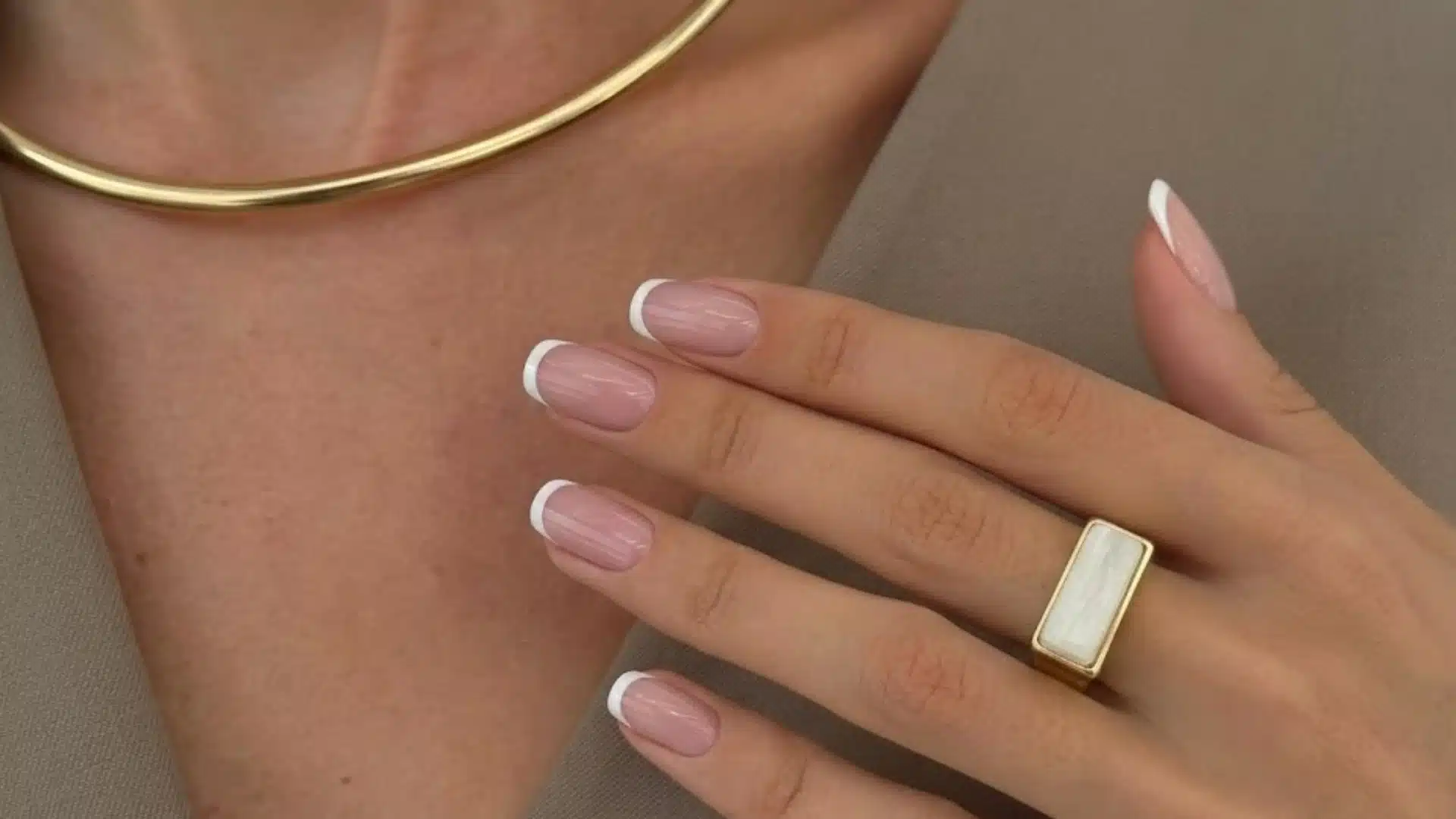 Hand with Fine Line Tips nails in soft pink base, thin white French tips on short oval nails