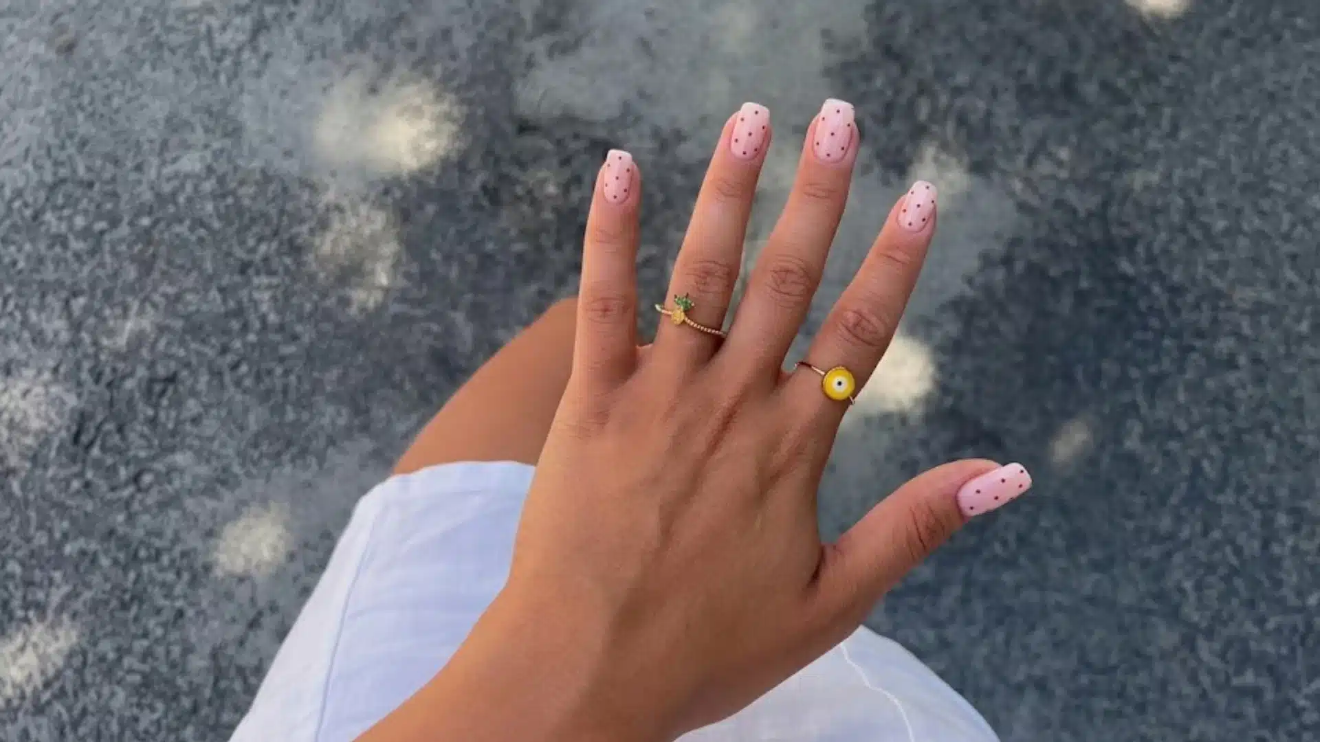 Hand with Micro Dot nails in soft pink polish, tiny dotted pattern on square tips, minimal chic nail art style