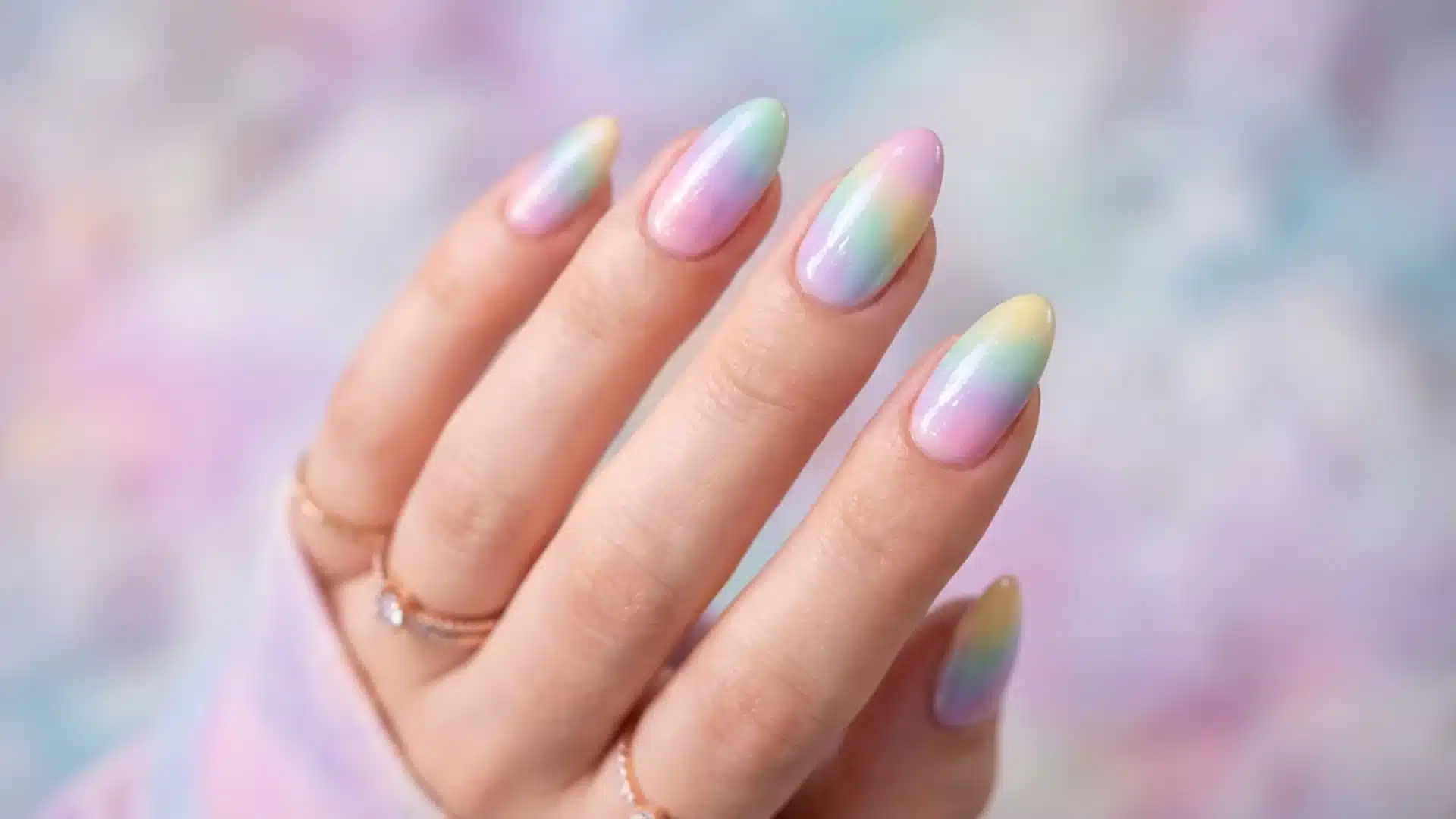 Hand with Rainbow Mist nails in soft pastel gradient blend, glossy almond shape