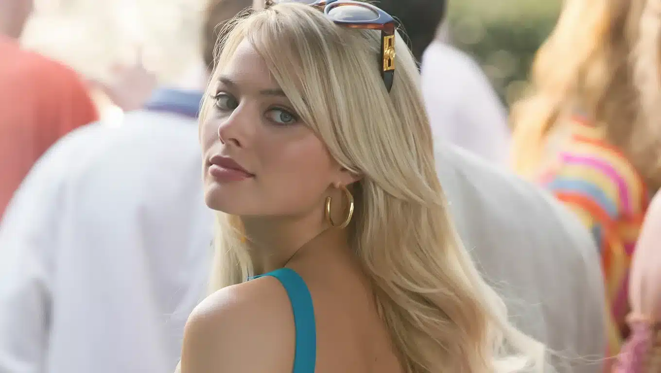 Margot Robbie with soft makeup and gold hoops looking back, styled in light summer tones with a fresh, airy aesthetic