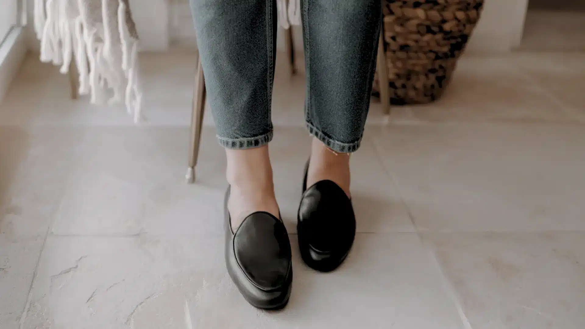 Minimal black Belgian loafers worn with cuffed jeans indoors clean sleek everyday casual footwear look