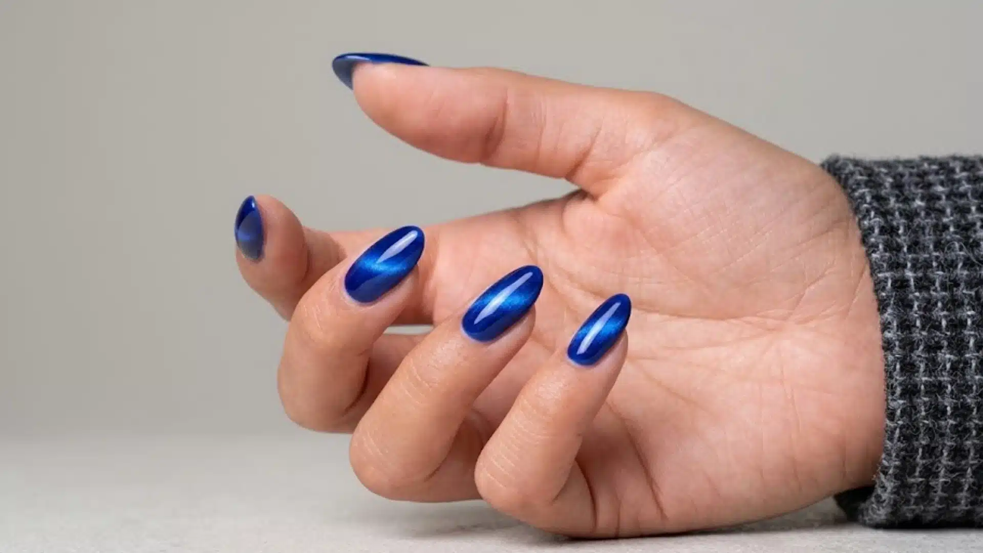Mirror Edge Nails with almond nails in deep blue magnetic cat eye finish, glossy shine, smooth reflective wave effect
