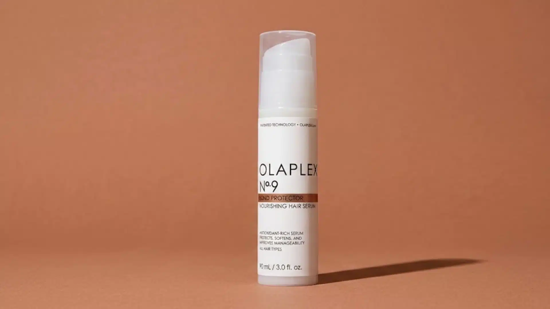Olaplex No 9 Bond Protector hair serum bottle on a warm terracotta background with soft shadow