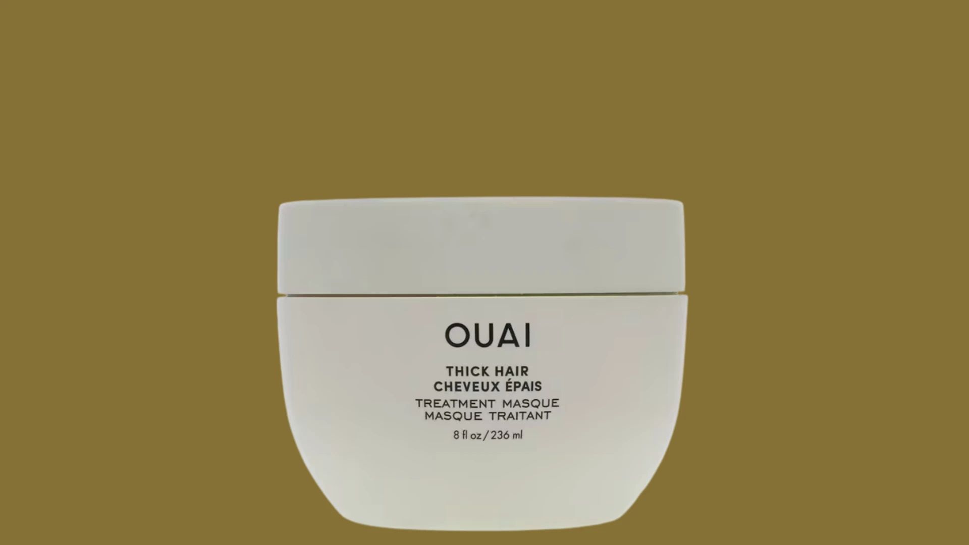 Ouai thick hair treatment masque in a white jar against an olive green background