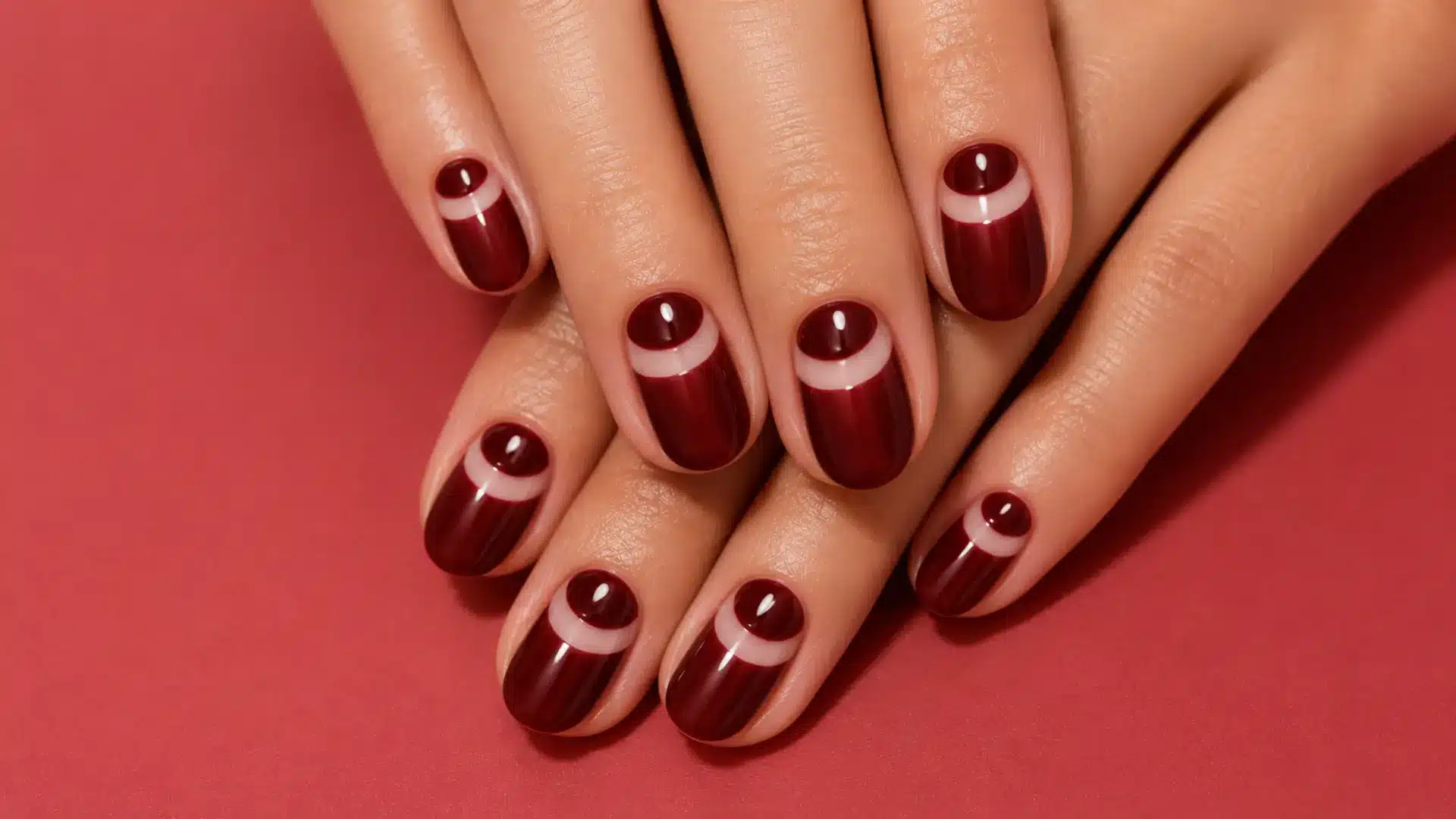 Oval nails with deep burgundy half-moon reverse French accent at the nail base