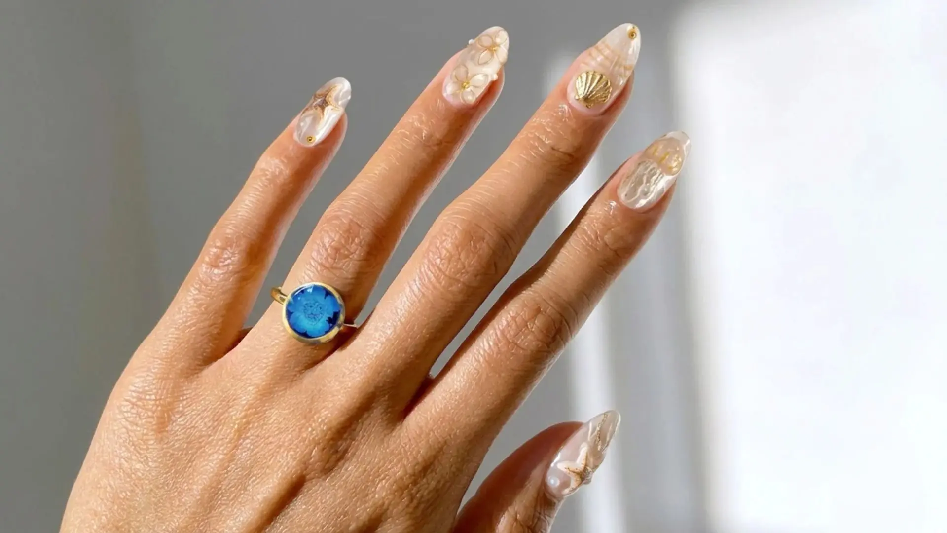 Pearl and seashell inspired nail art with gold accents on neutral base for elegant beach themed manicure
