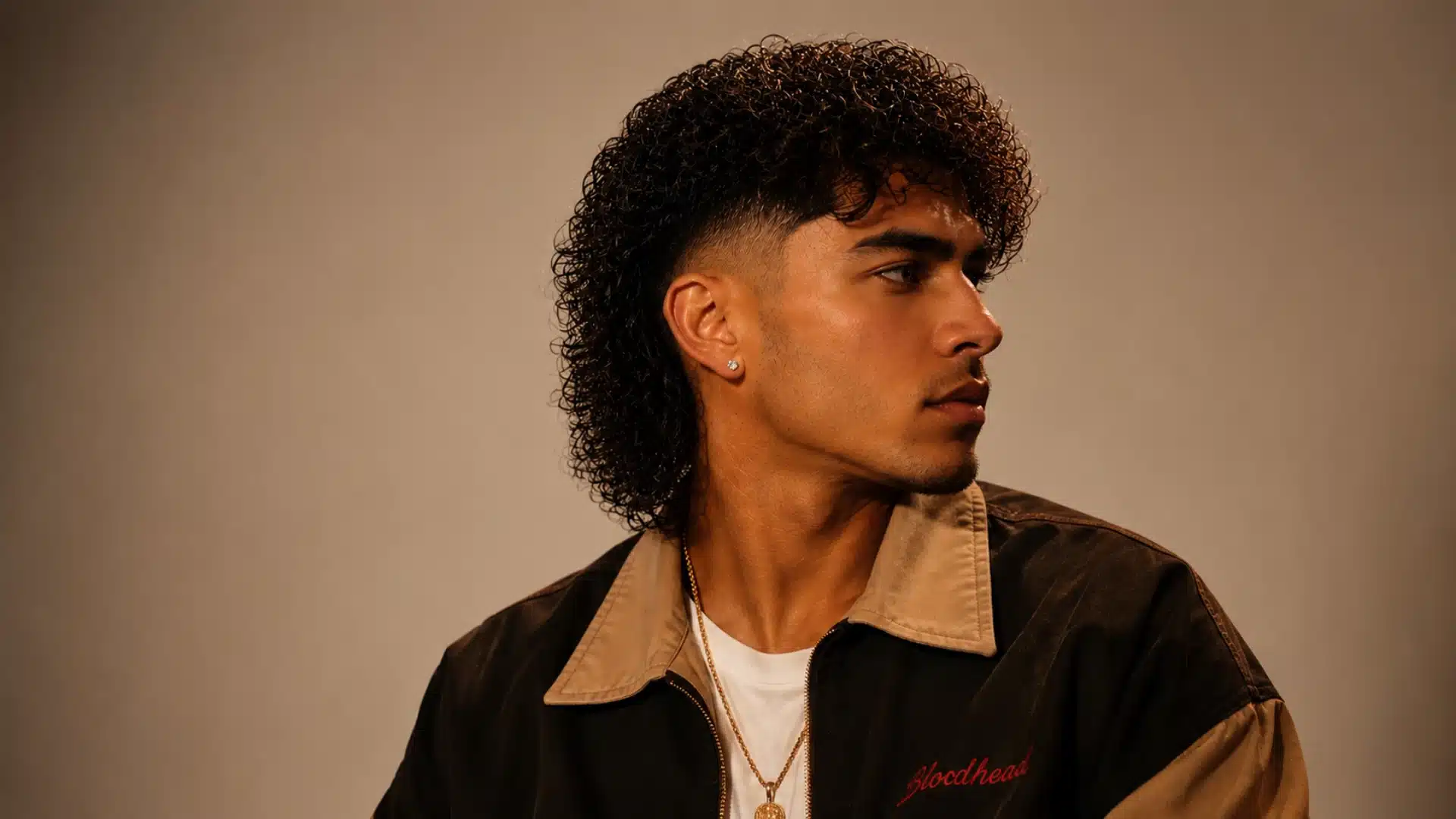 Permed mullet fade with defined curly texture, tapered sides, and voluminous layered back style