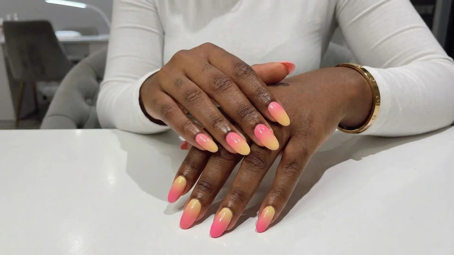 Pink to yellow tropical ombre nails on almond shape with glossy finish for vibrant summer nail design