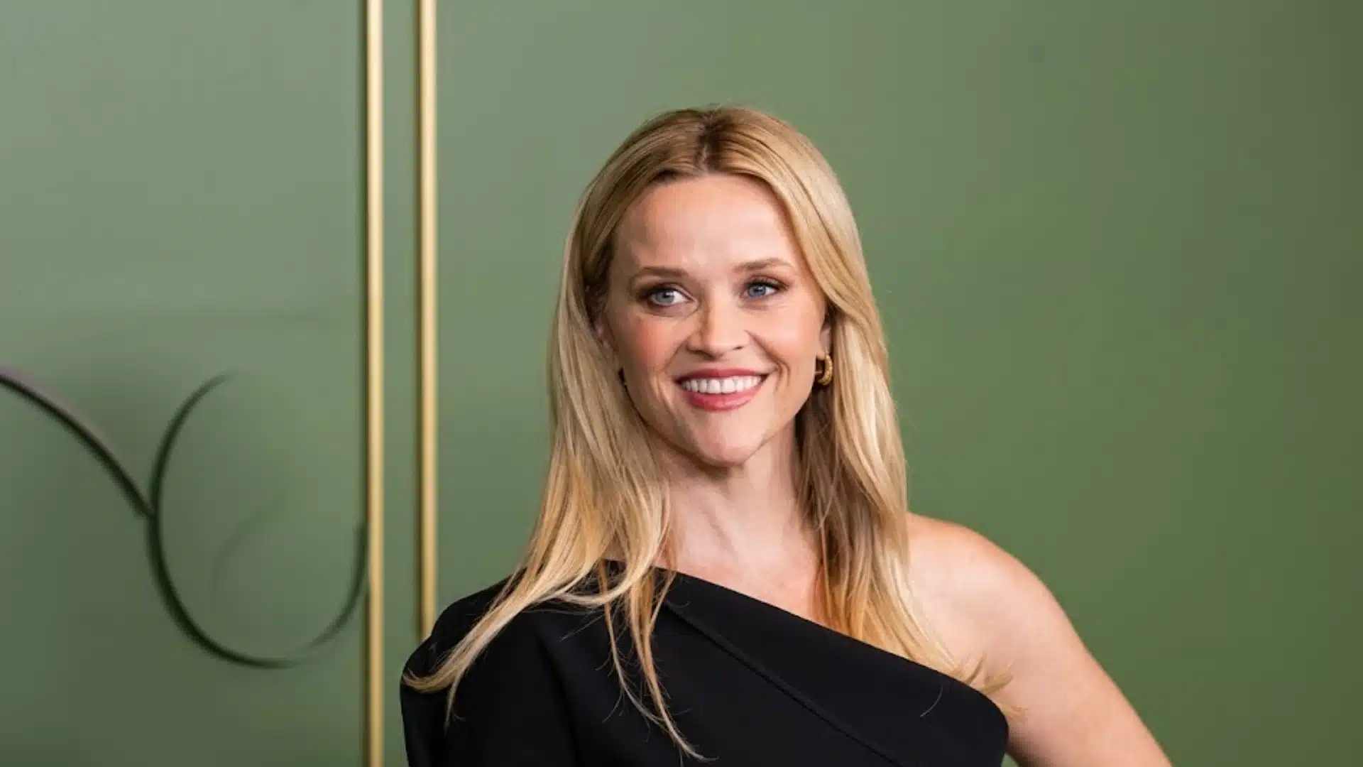 Reese Witherspoon smiling in black dress, showcasing light summer features with soft blonde hair
