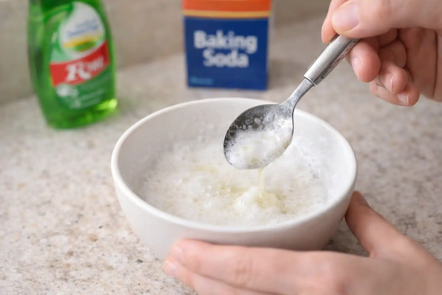 Small bowl of baking soda and dish soap mixture being stirred with a spoon for removing hair dye stains from skin