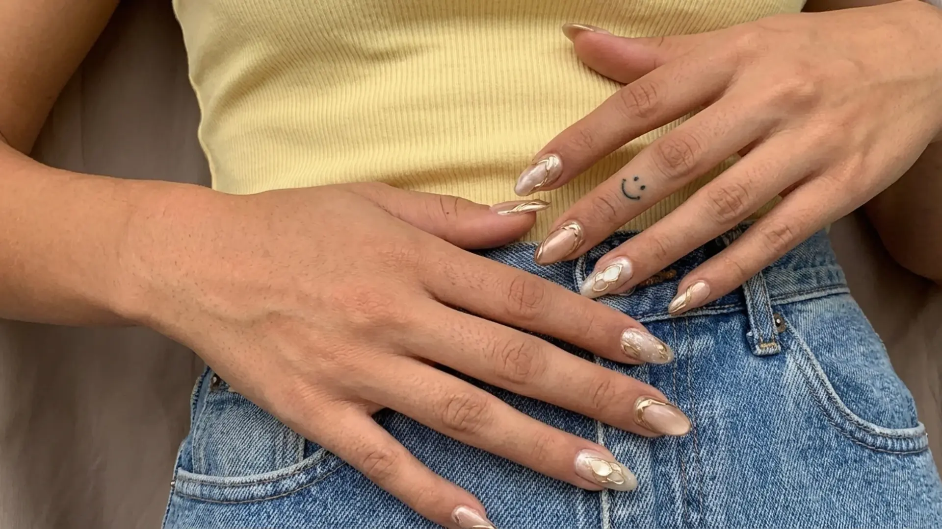 Soft nude gold accent nails on almond nails styled with denim outfit as modern bridemaids nail design idea
