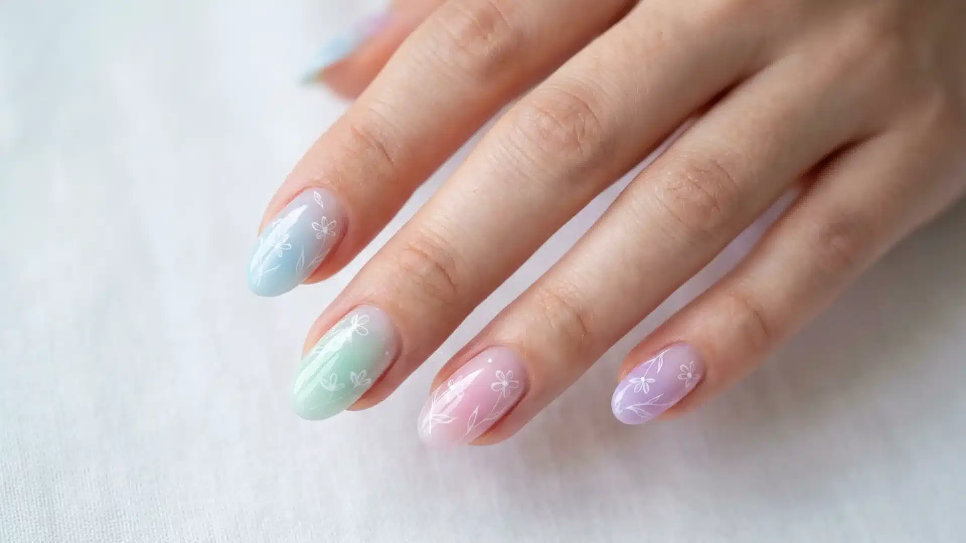 Spring Breeze nails featuring soft pastel gradient shades of blue, green, pink, and lilac with delicate white floral line art
