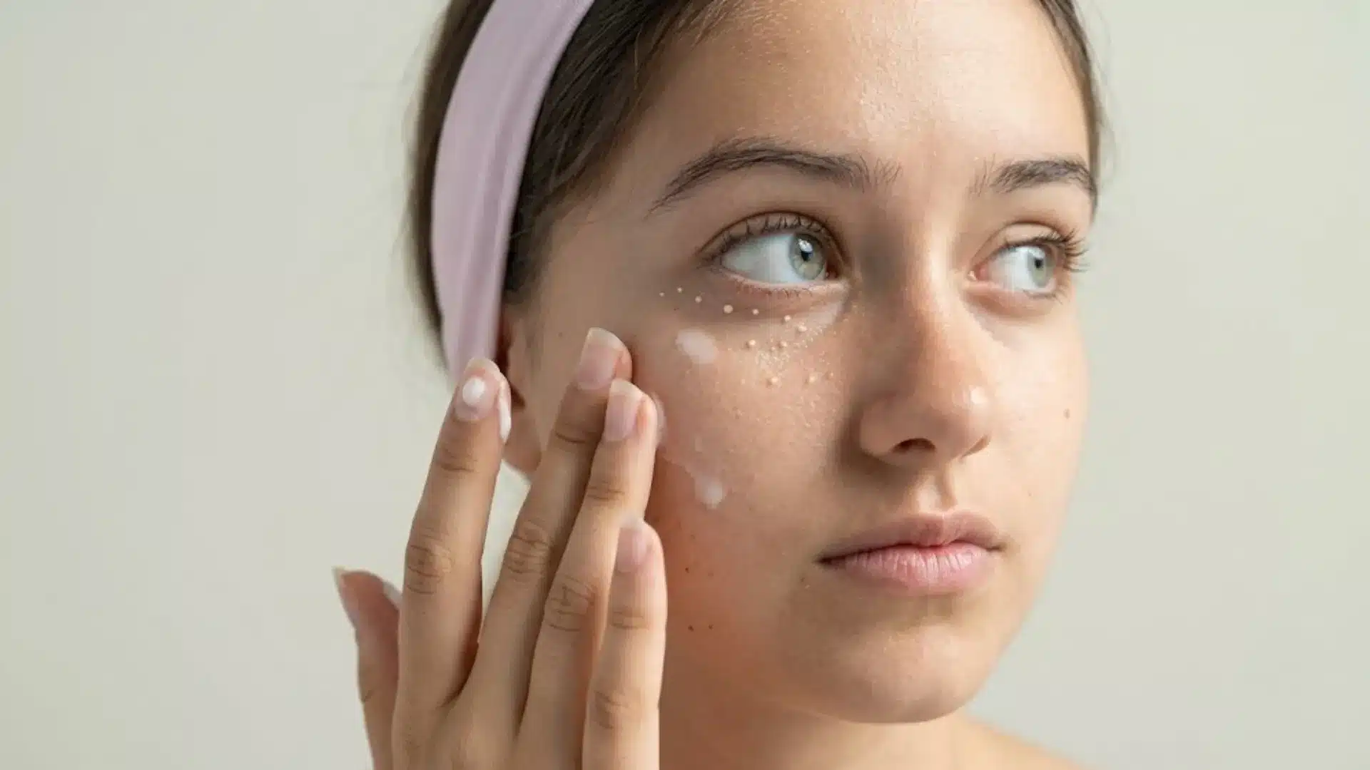 Woman applying face cream showing small milia bumps under her eye