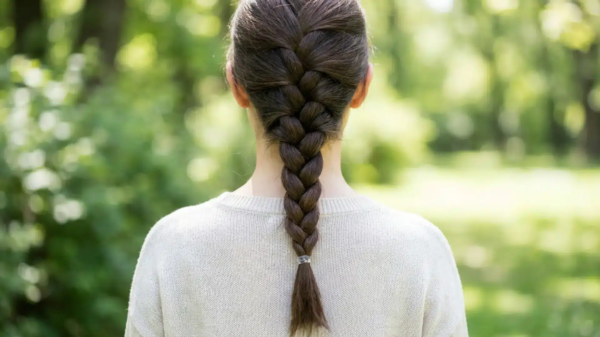 Woman from behind with a single neat three-strand classic braid running down her back