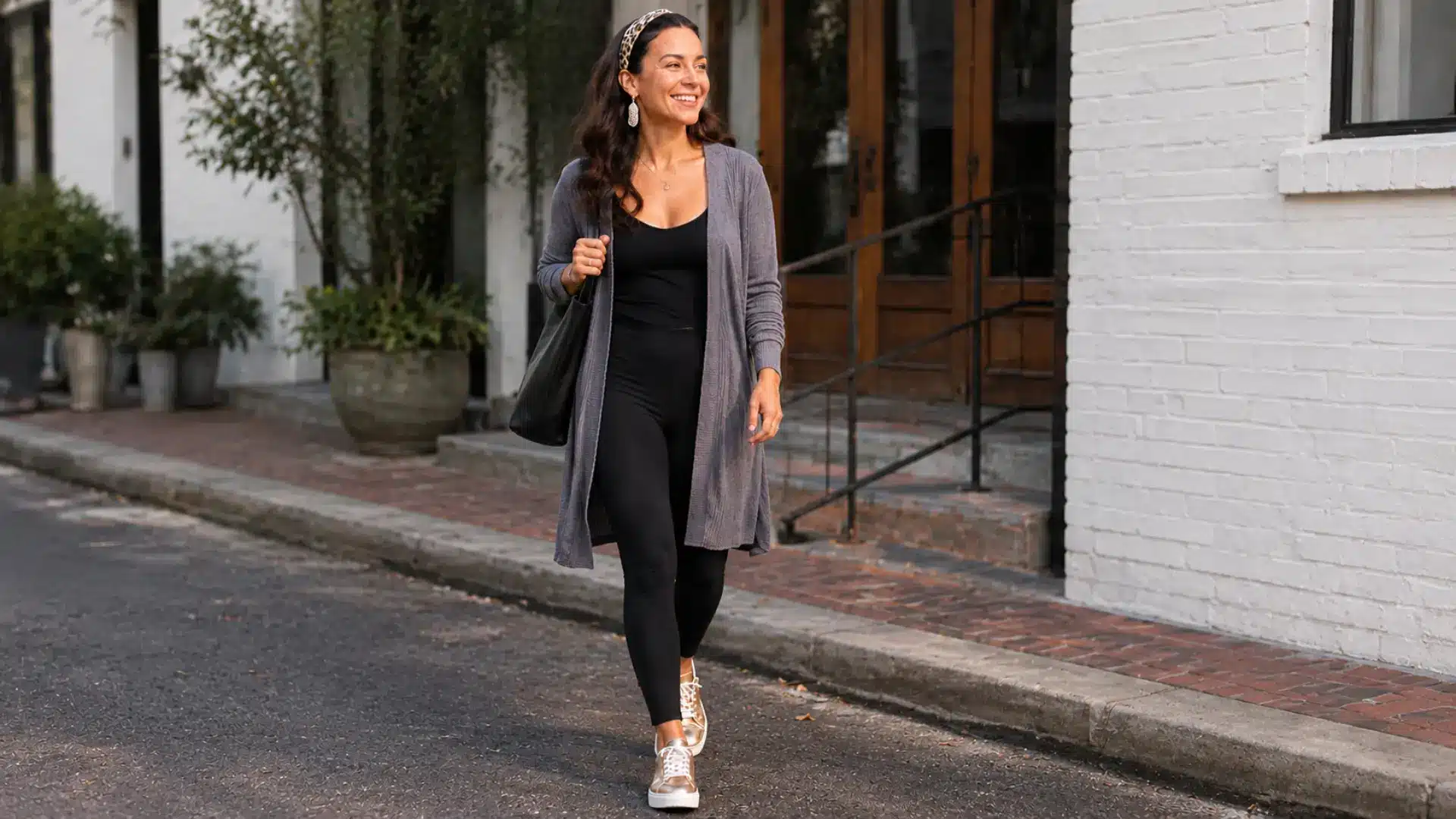 Woman in black leggings and gray cardigan walking through a realistic urban street setting