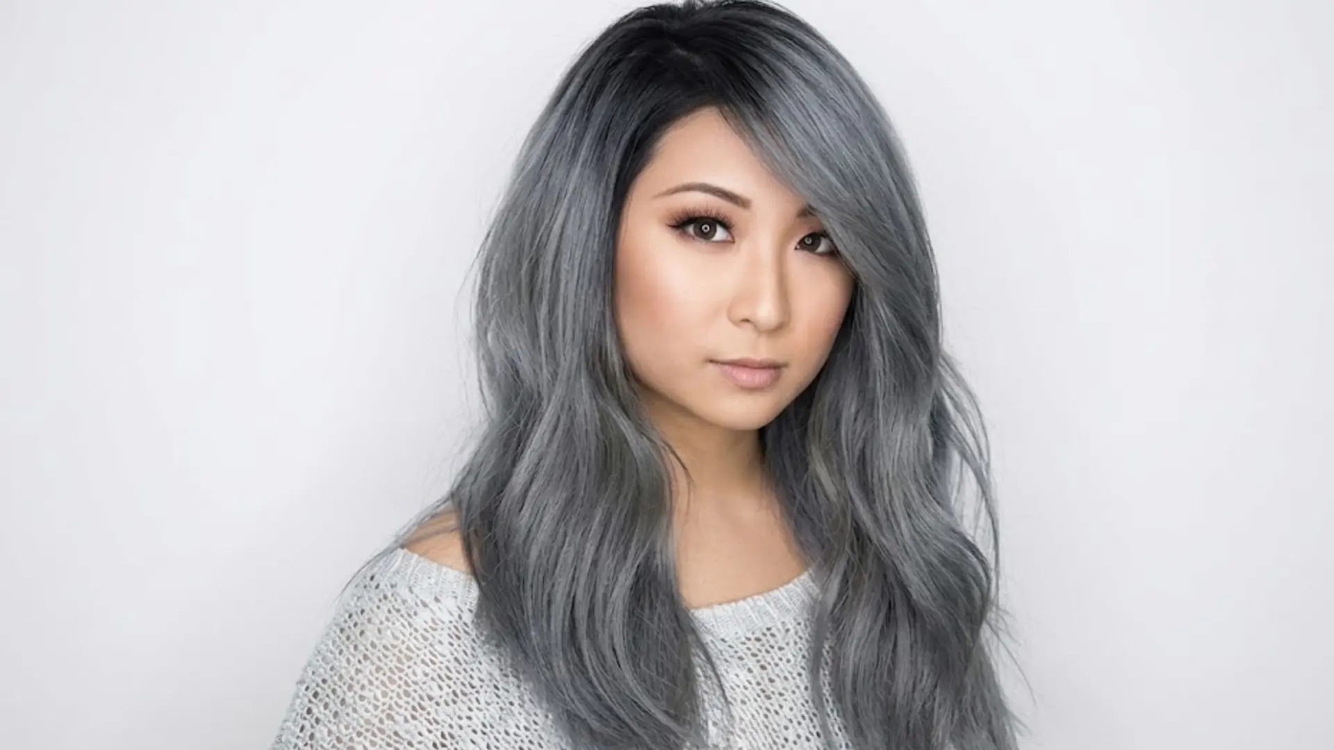 Woman with cool toned slate gray hair styled in soft waves, showing smooth texture and balanced cool shade