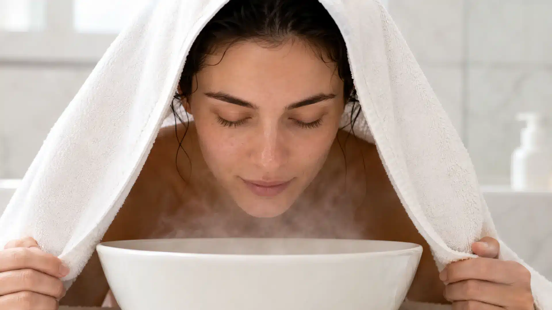 Woman steaming face at home as part of facial at home skincare routine