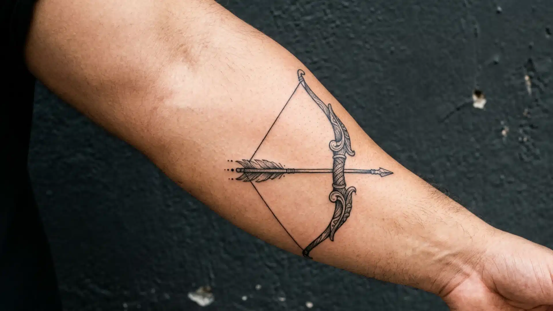 A highly detailed, ornate bow and arrow tattoo inked on a man's inner forearm, pointing toward his hand