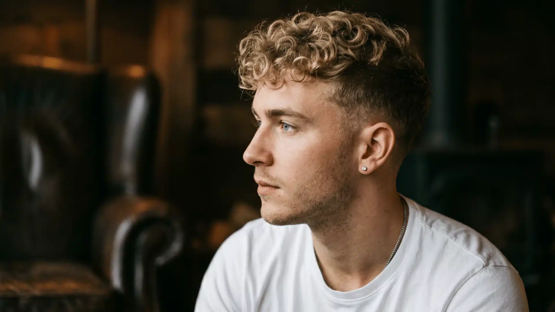 Bearded man with a curly medium buzz cut featuring defined curls and faded sides