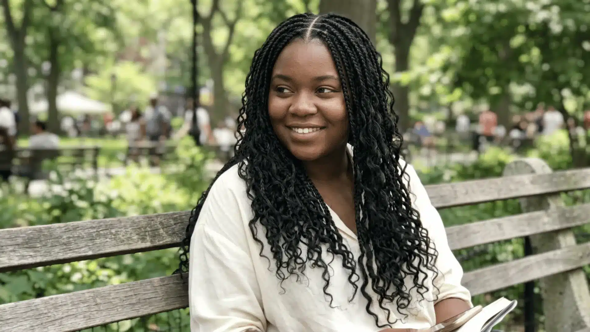 _Boho braids with a clean middle part falling evenly on both sides with natural black color and loose curly ends on a park bench