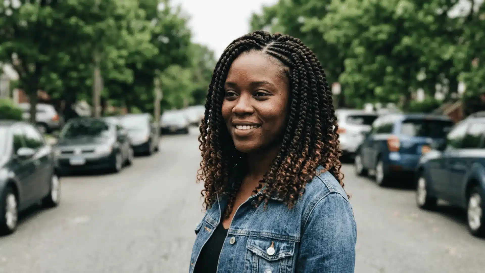 Boho crochet braids in natural brown with uniform curly ends and shoulder length installed over a cornrow base on a woman on a road