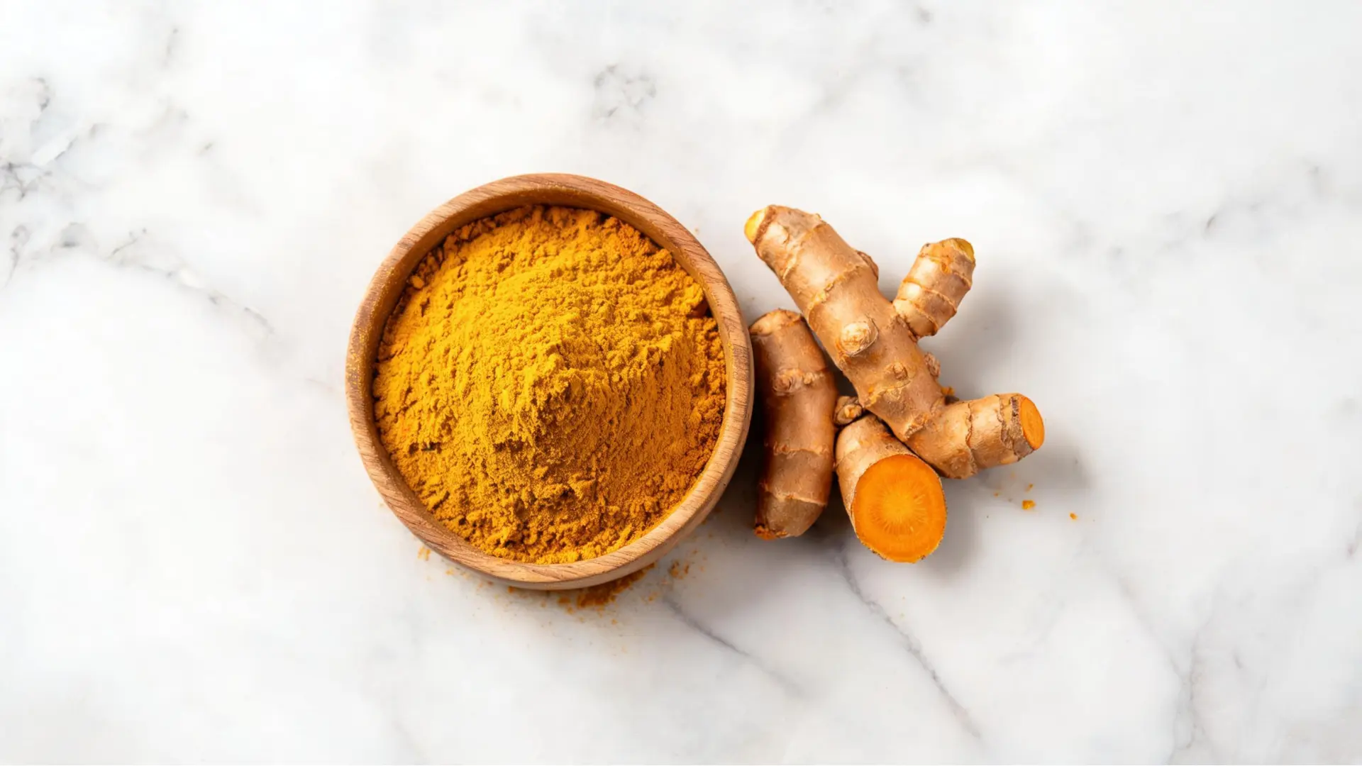 Bowl of turmeric powder with fresh turmeric root.
