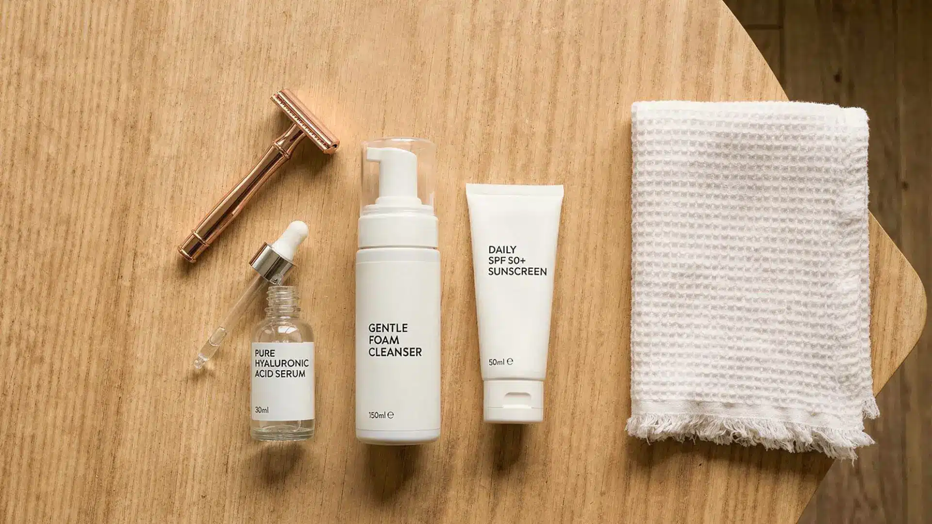 Dermaplaning tools laid out including razor, hyaluronic serum, cleanser and SPF
