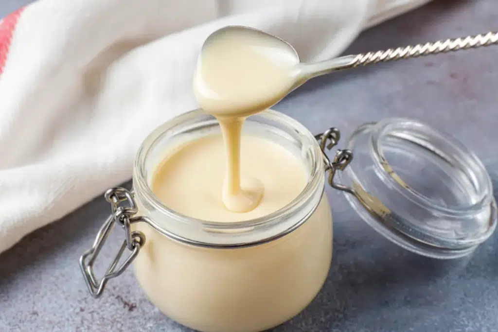Glass jar of beef tallow on white marble surface for skincare use