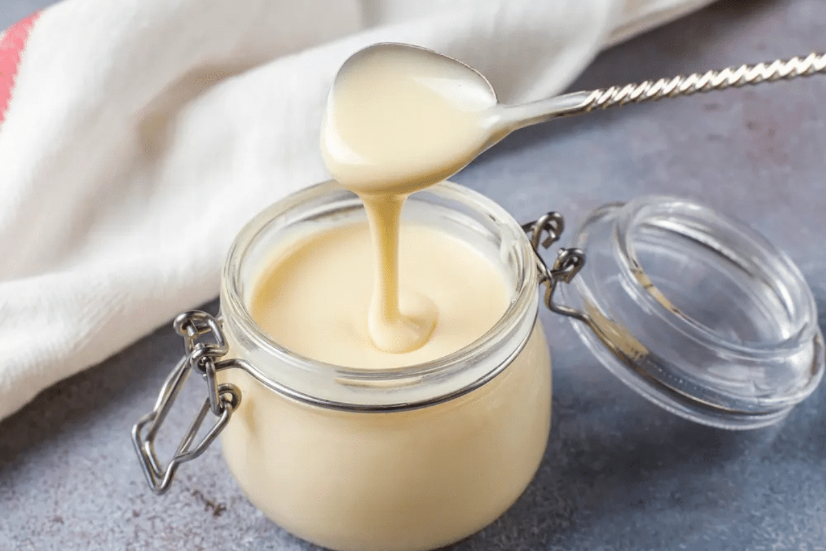 Glass jar of beef tallow on white marble surface for skincare use