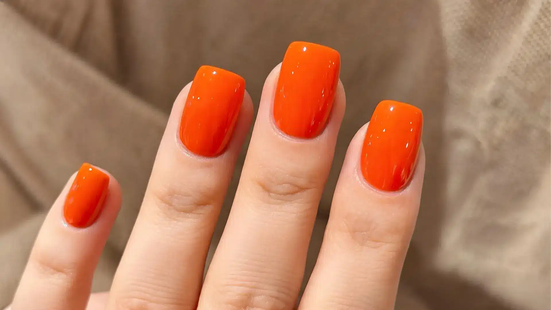 Glossy bright orange square nails close up