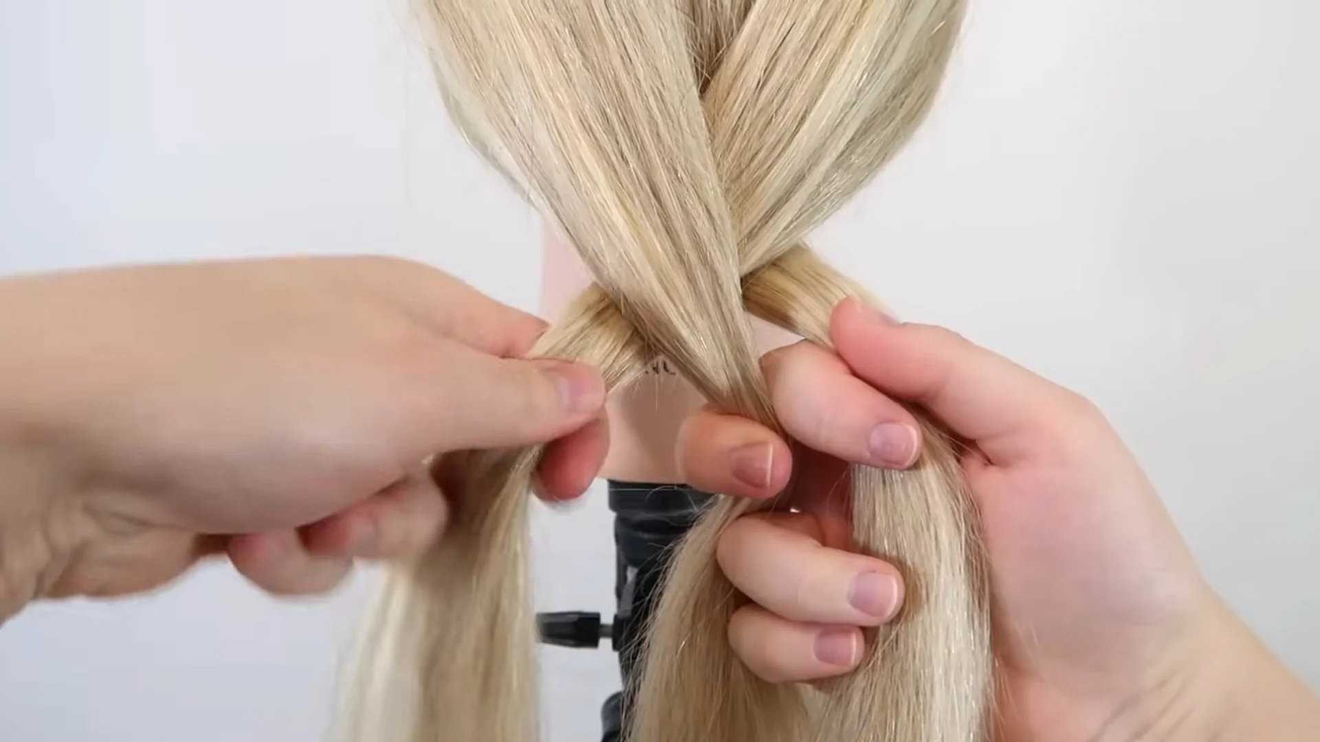 Hands dividing blonde hair into three equal sections before starting a basic three-strand braid.