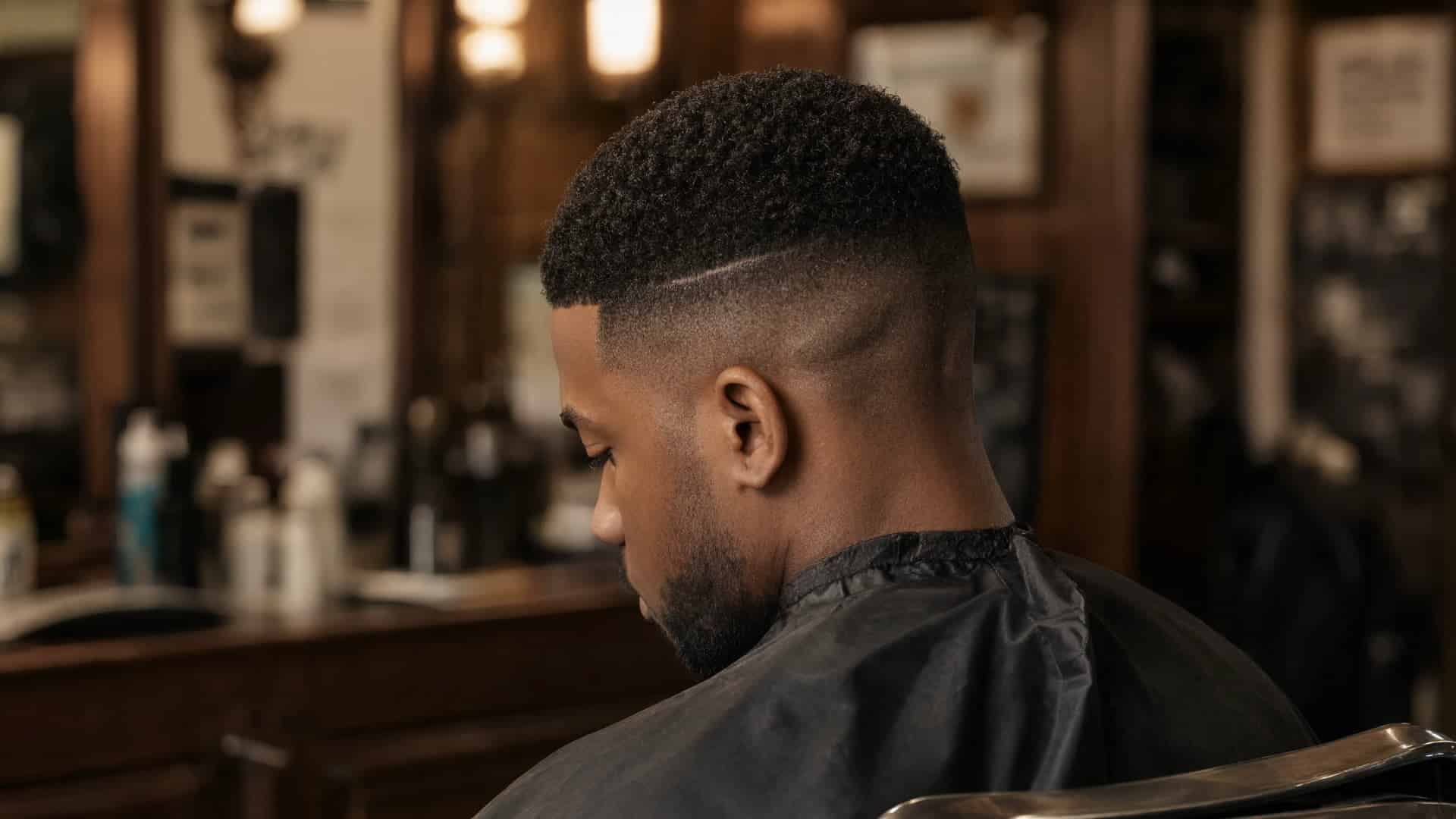 Man from the side showing a fresh skin fade and surgical line in a barbershop