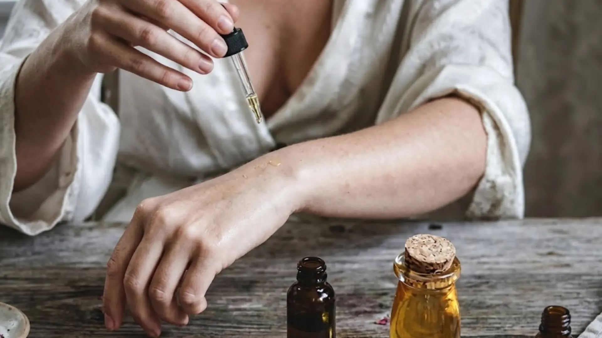 Person applying coconut oil to arm with a dropper for eczema skin care