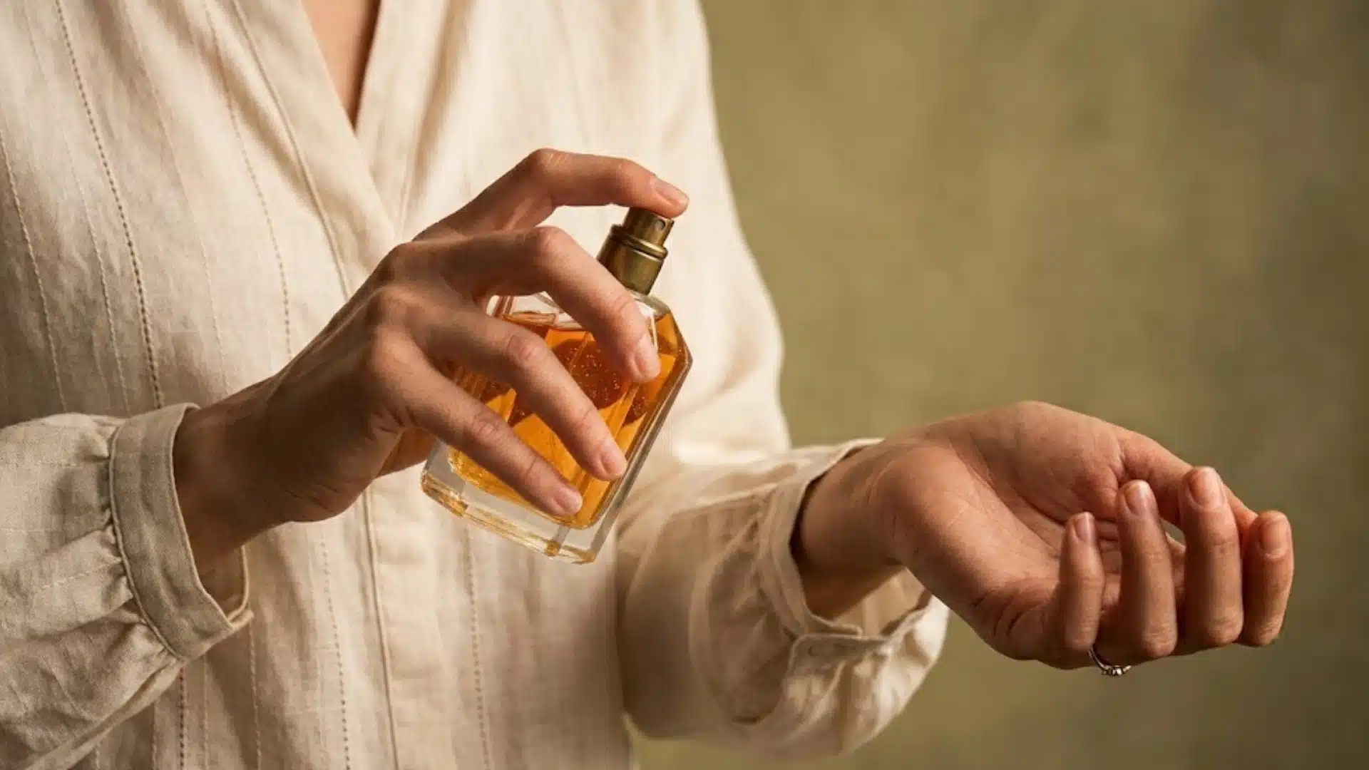 Person spraying eau de toilette on wrist from a glass perfume bottle for daily fragrance use
