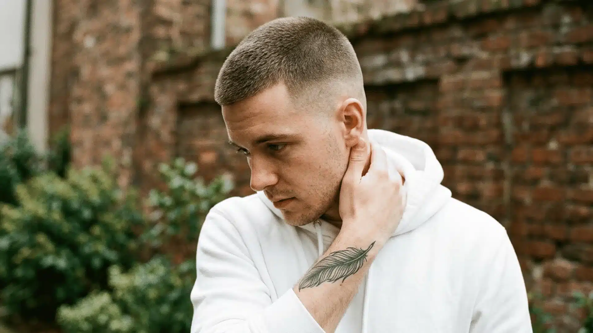 Rugged man with a crew cut buzz featuring a longer textured top and faded sides