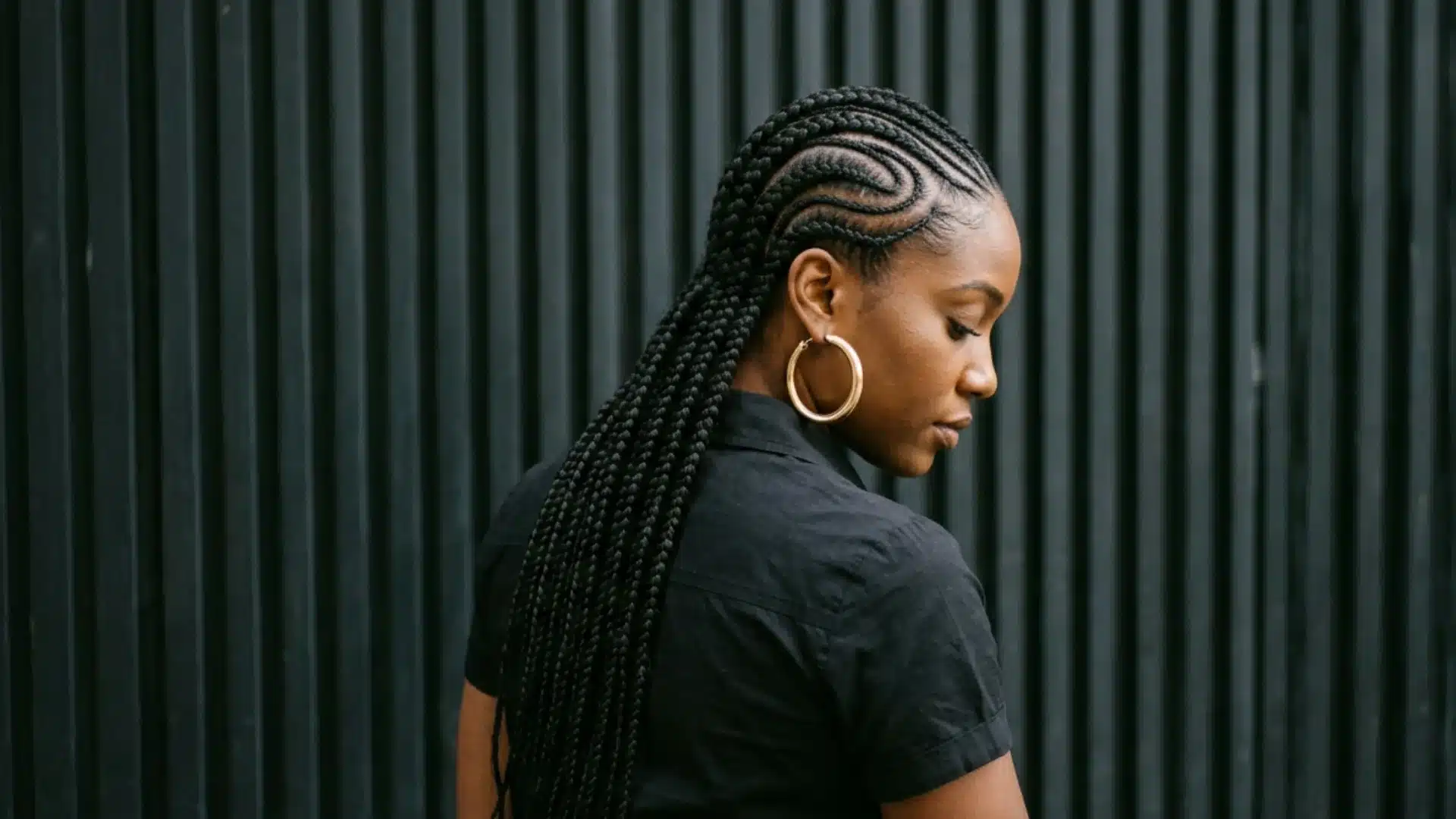 Side profile of a woman looking down, showcasing sleek straight-back cornrows with a wavy side-part design