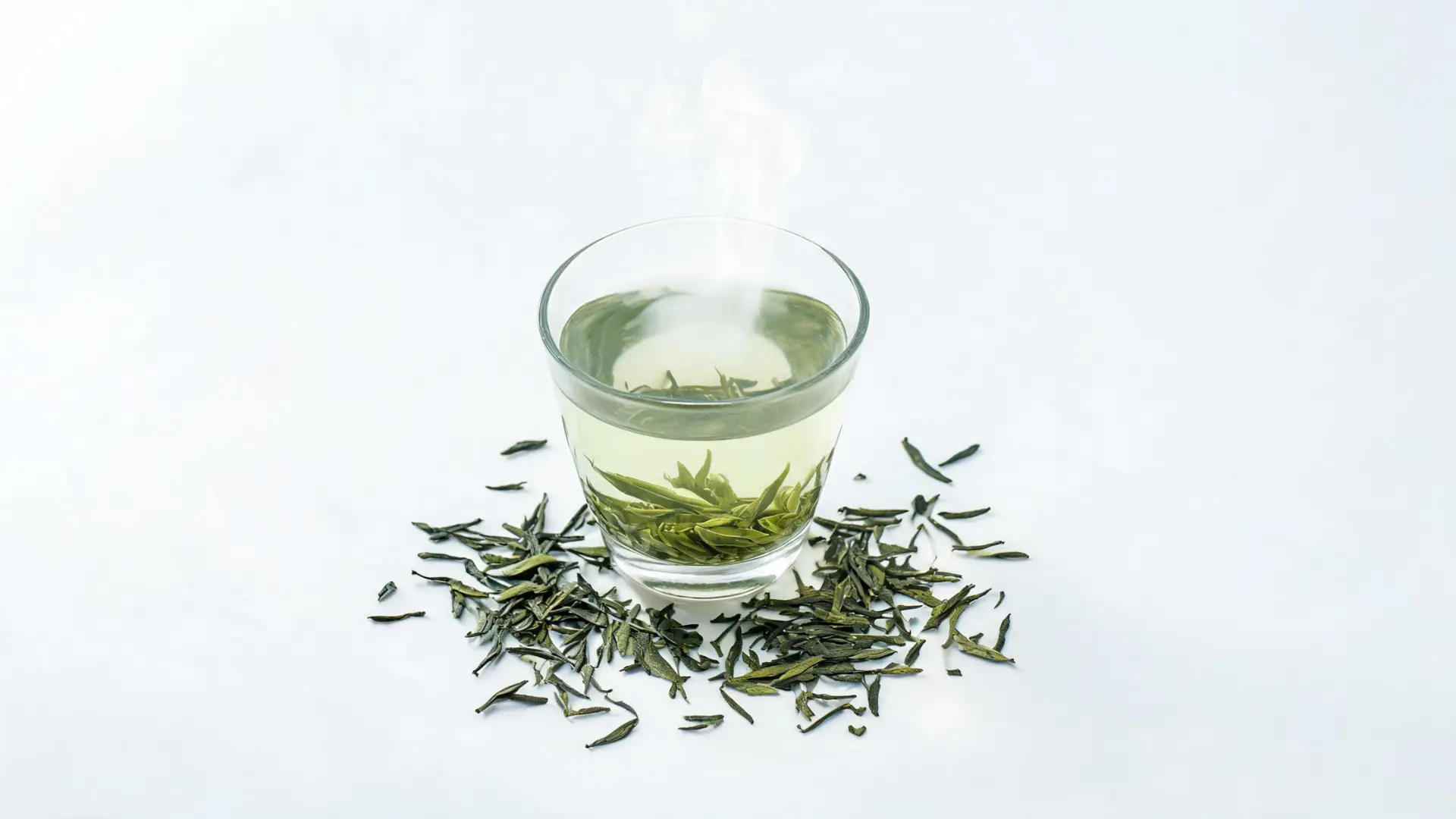 Steaming green tea with loose tea leaves.