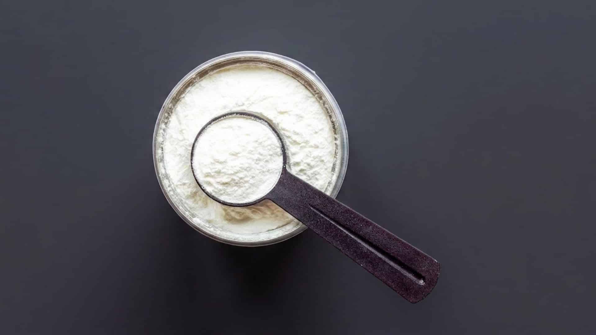 Top-down view of a creatine scoop in a tub, isolated on a dark gray background