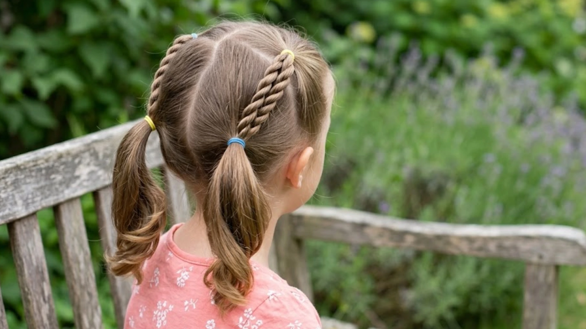 Young girl with twisted ponytail braids sitting on a wooden bench in a garden setting
