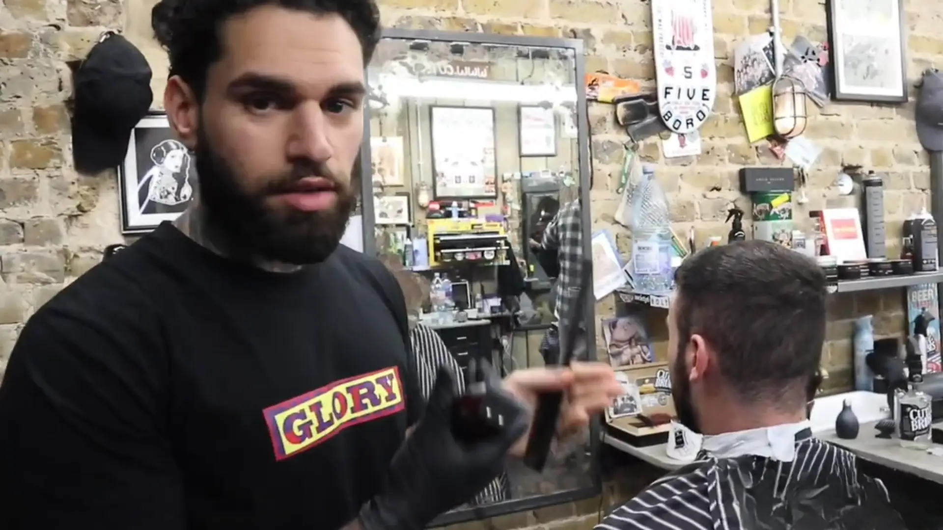 Barber holding clipper and comb while cutting man hair in vintage barbershop with mirror and tools