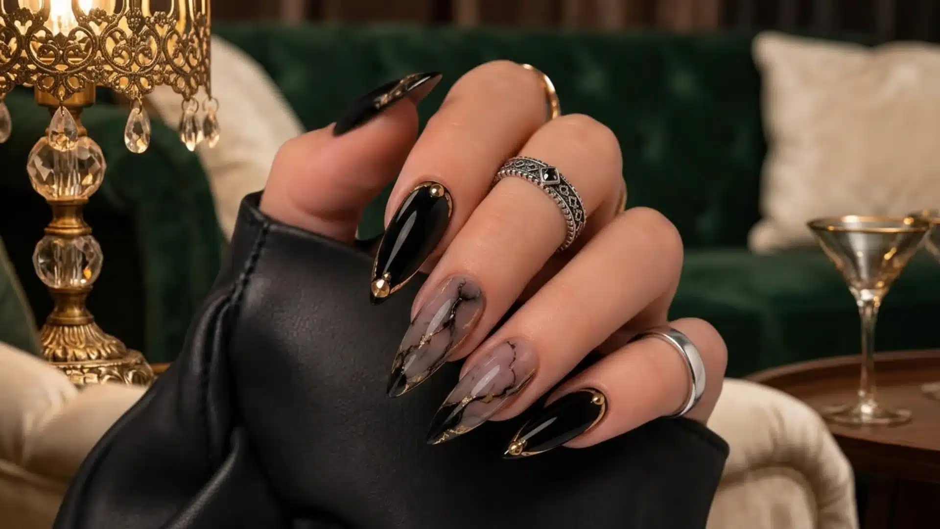 black and gold marble almond nails with glossy finish and metallic accents on hand in luxury indoor setting