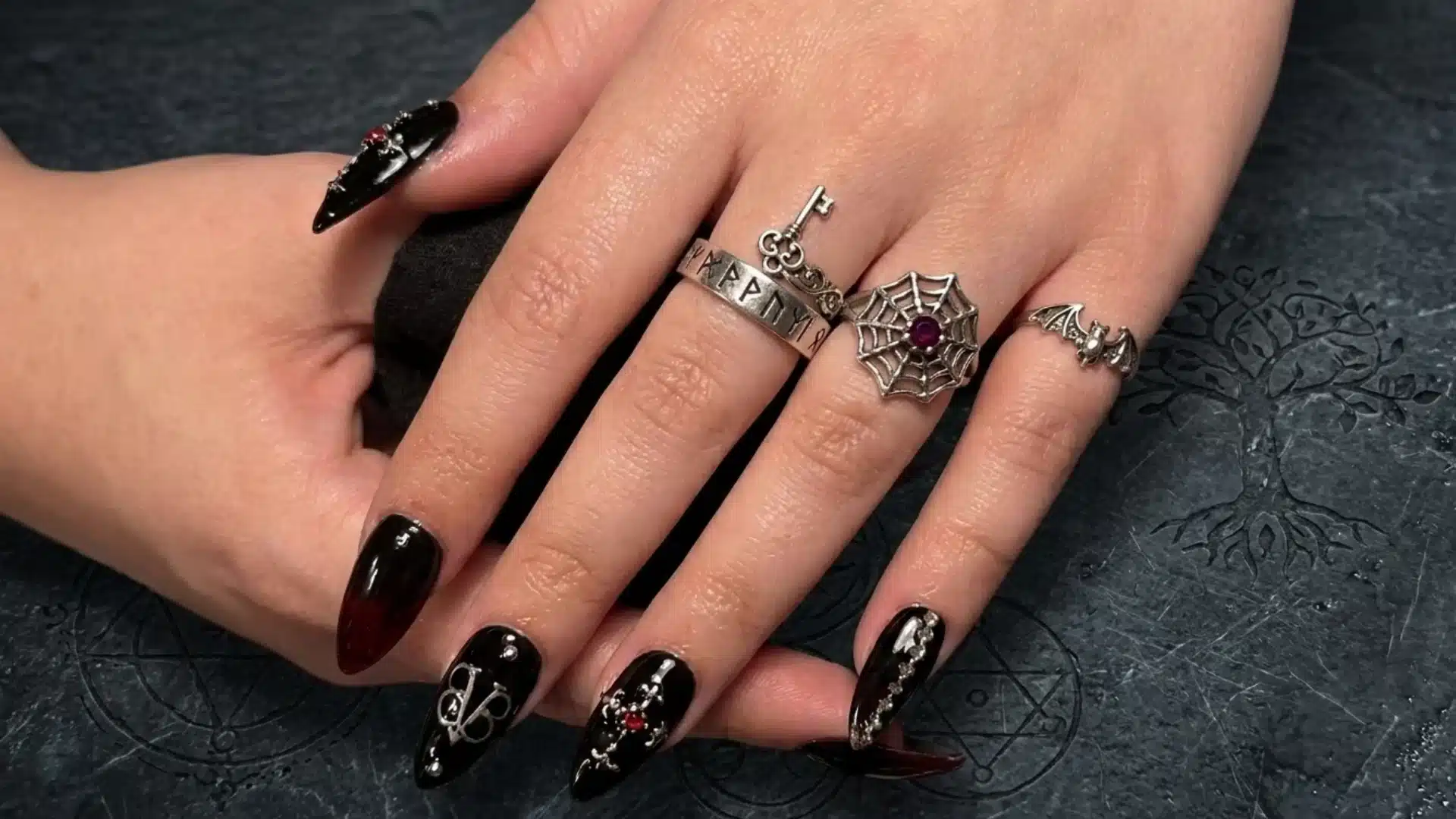 black veil almond nails with glossy black polish silver gothic details and charm accents on hand