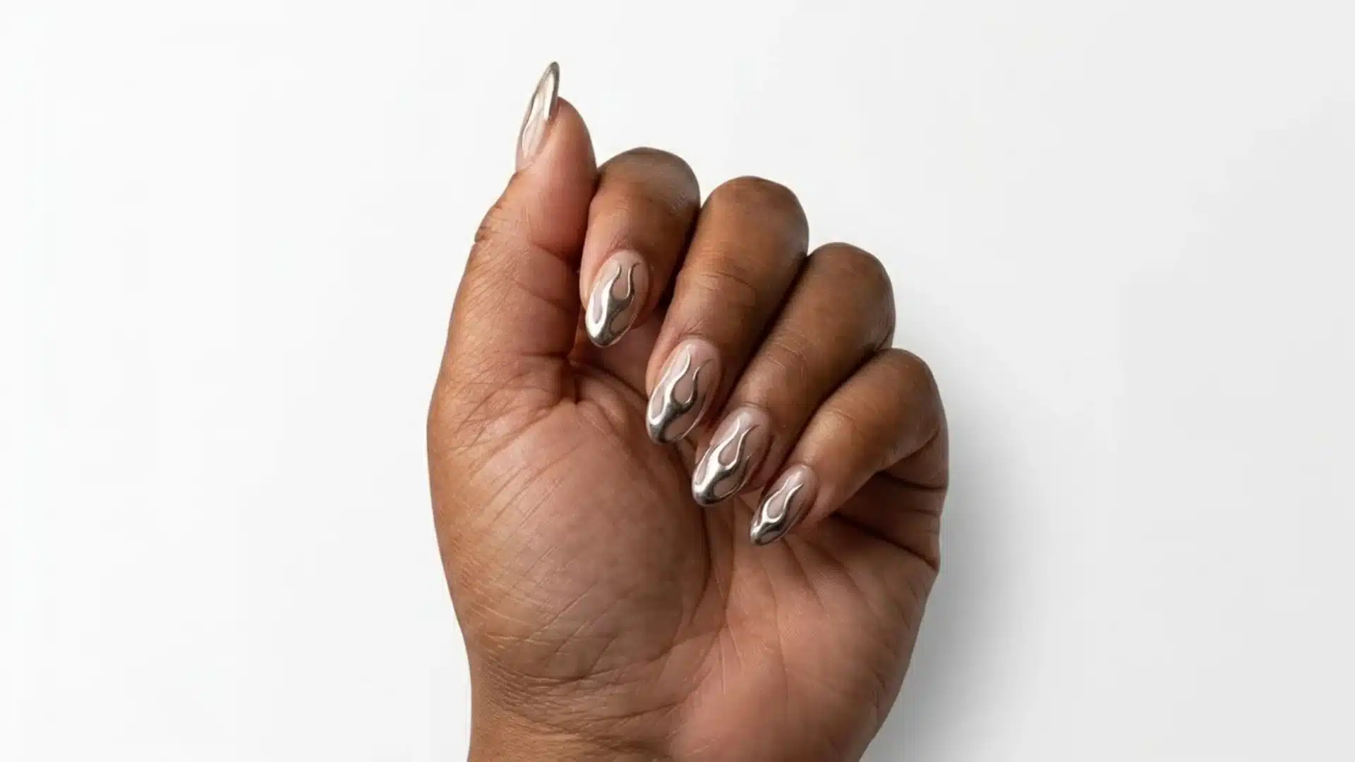 chrome flame almond nails with silver metallic flame designs on dark skin hand against white background