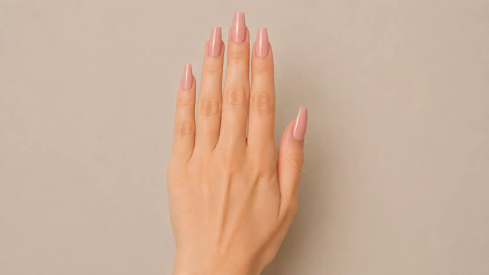 Close-up of a hand with glossy nude-pink coffin-shaped nails featuring tapered sides and flat, straight tips