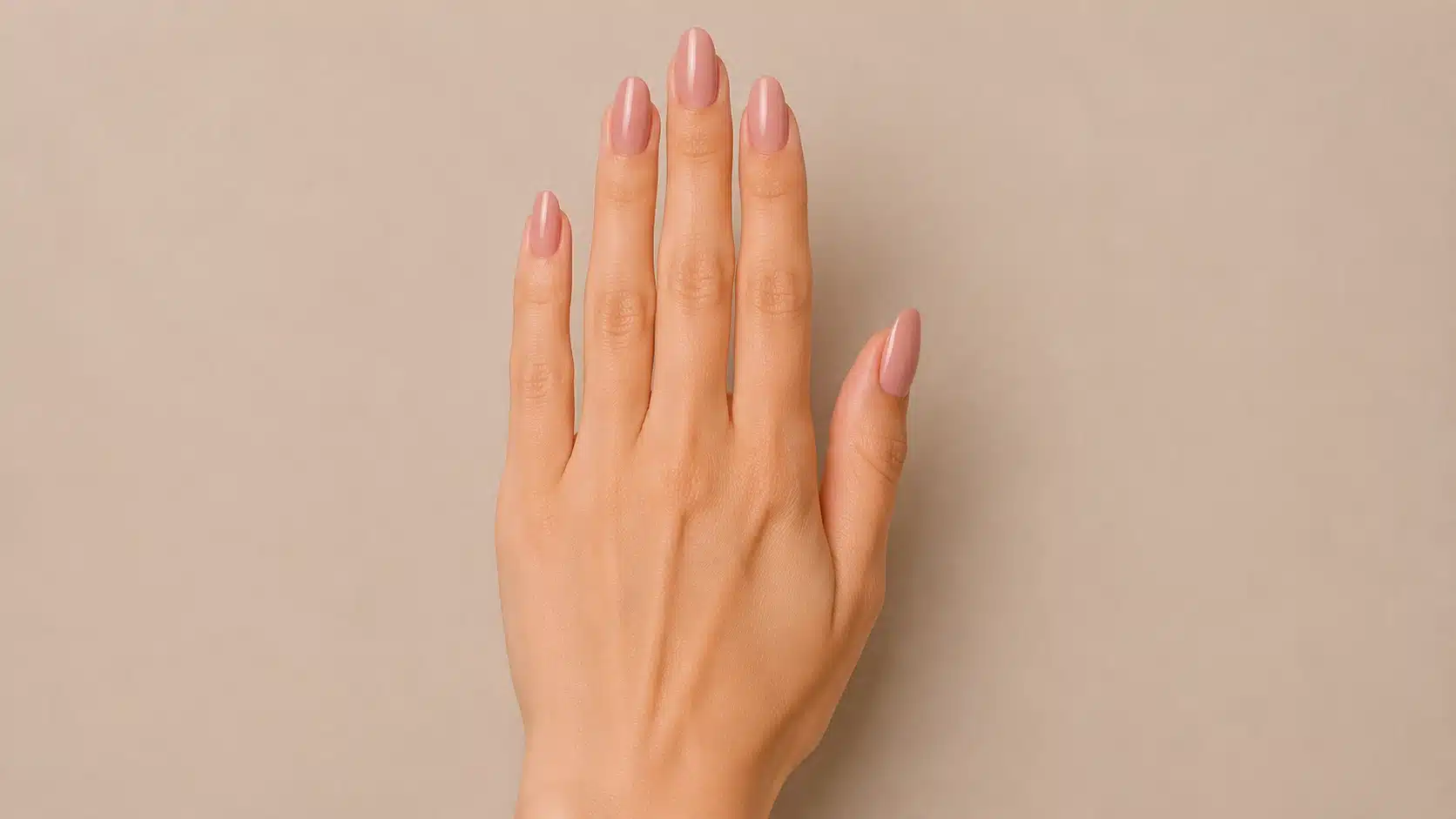 Close-up of a hand with glossy nude-pink oval-shaped nails featuring elongated sides and smoothly rounded tips.
