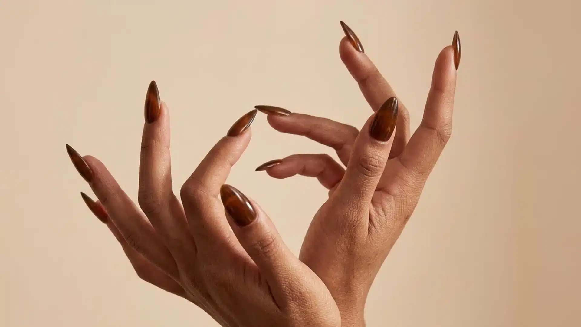 espresso brown almond nails with glossy finish on hands posed against a soft neutral background
