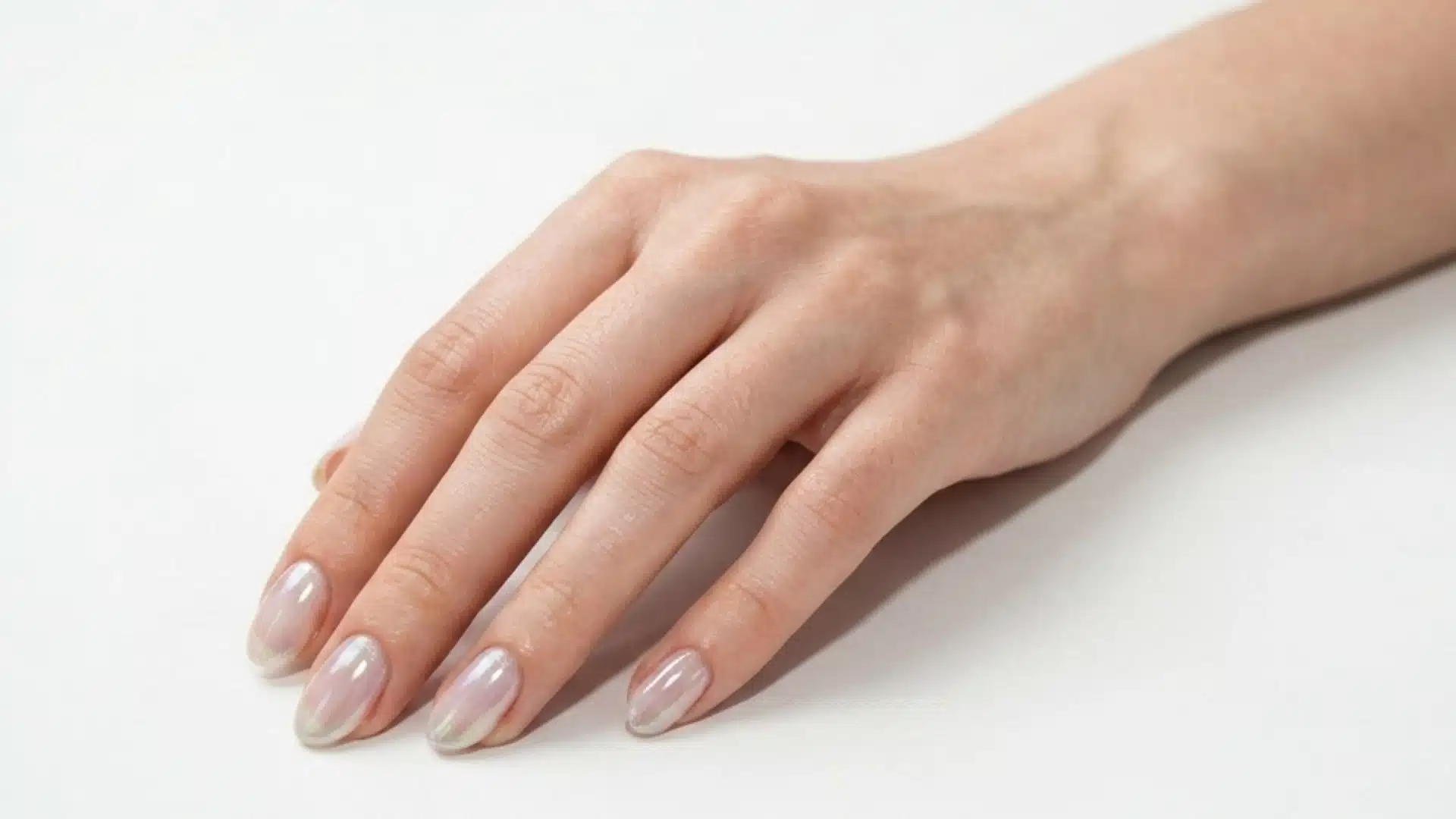 glass effect almond nails with sheer pearly polish and subtle iridescent shine on a natural hand