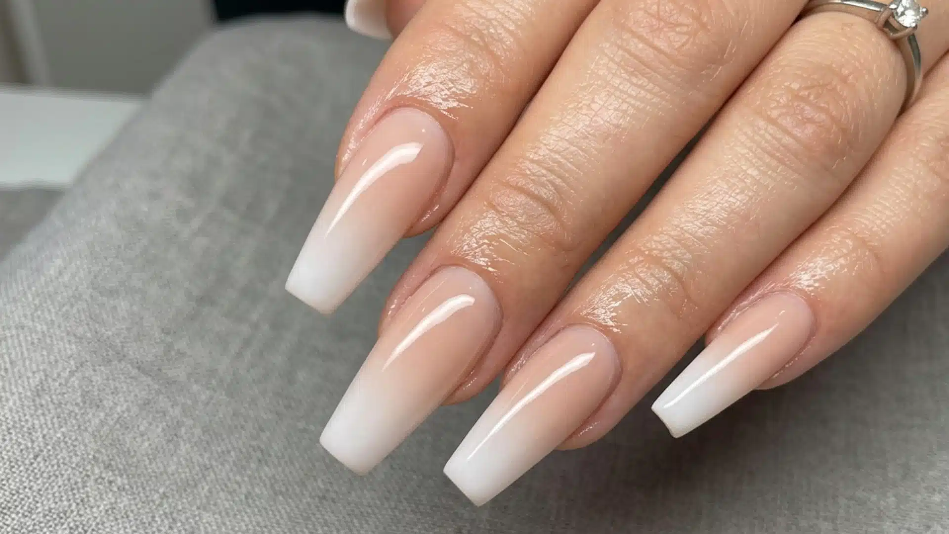 It shows long coffin-shaped nails with a glossy nude-to-white ombre finish